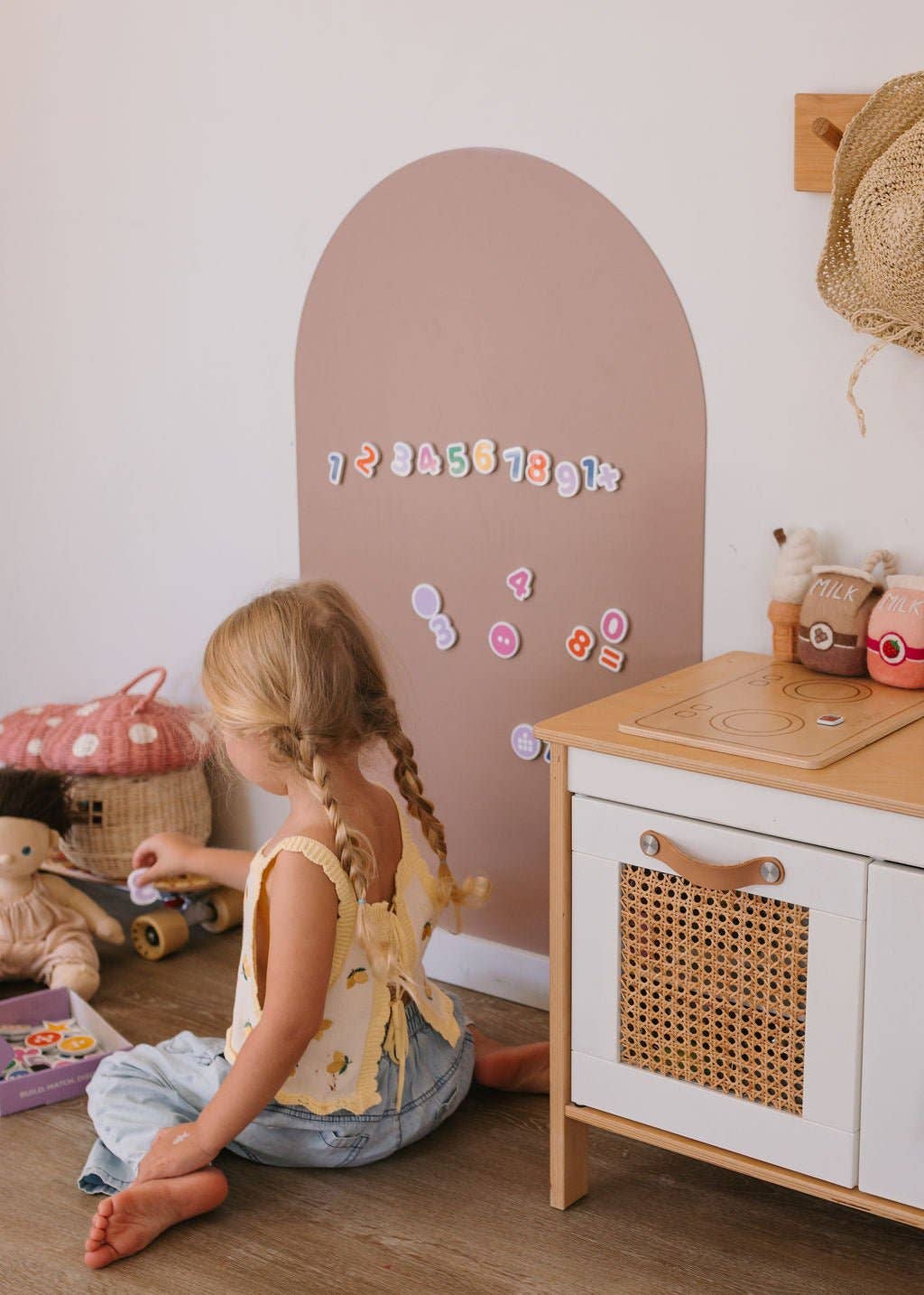 Child playing in a room with a wooden cabinet and decorative wall.