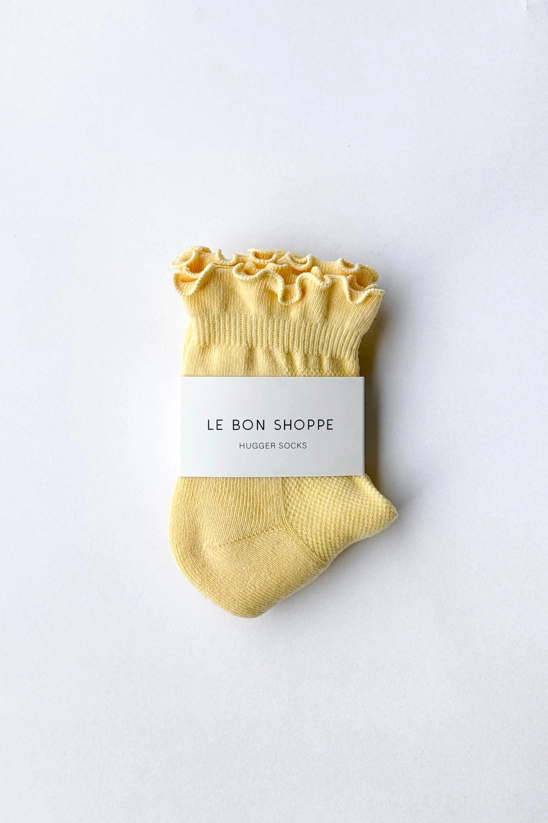 Yellow sock with ruffled top on a white background, labeled 'Le Bon Shoppe'.