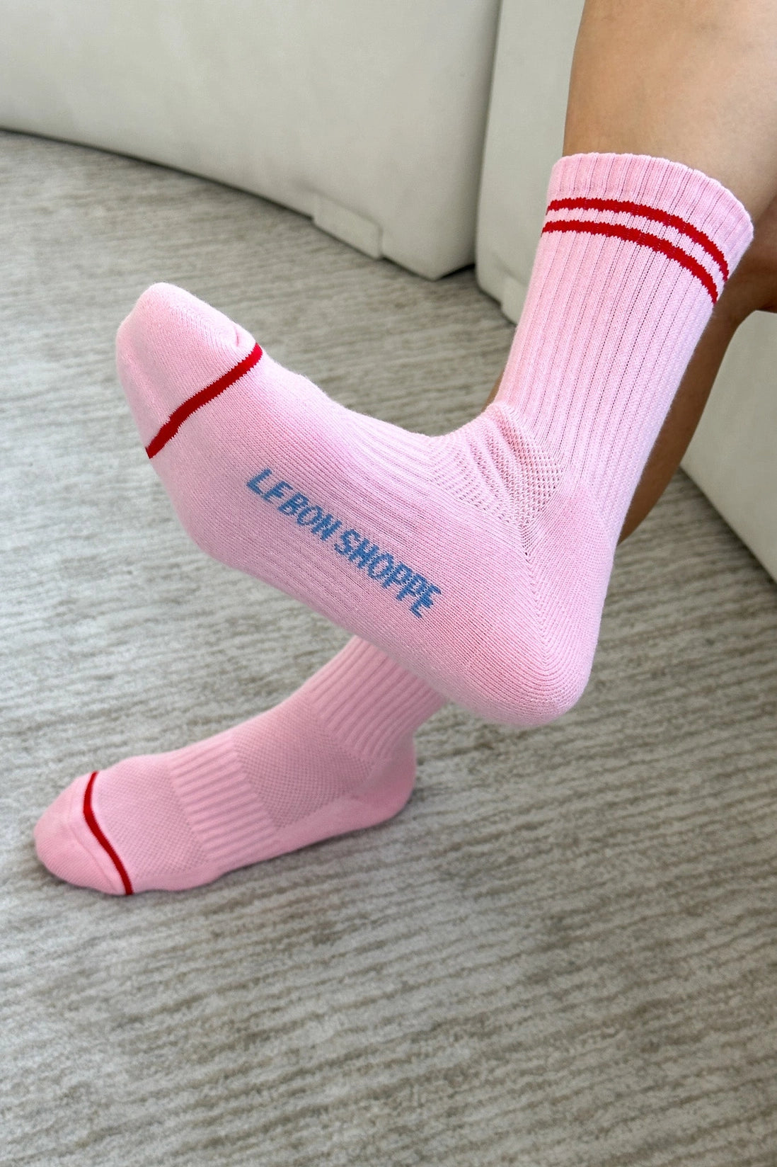 Pink socks with red stripes and 'LEBON SHOPPE' text on a neutral background