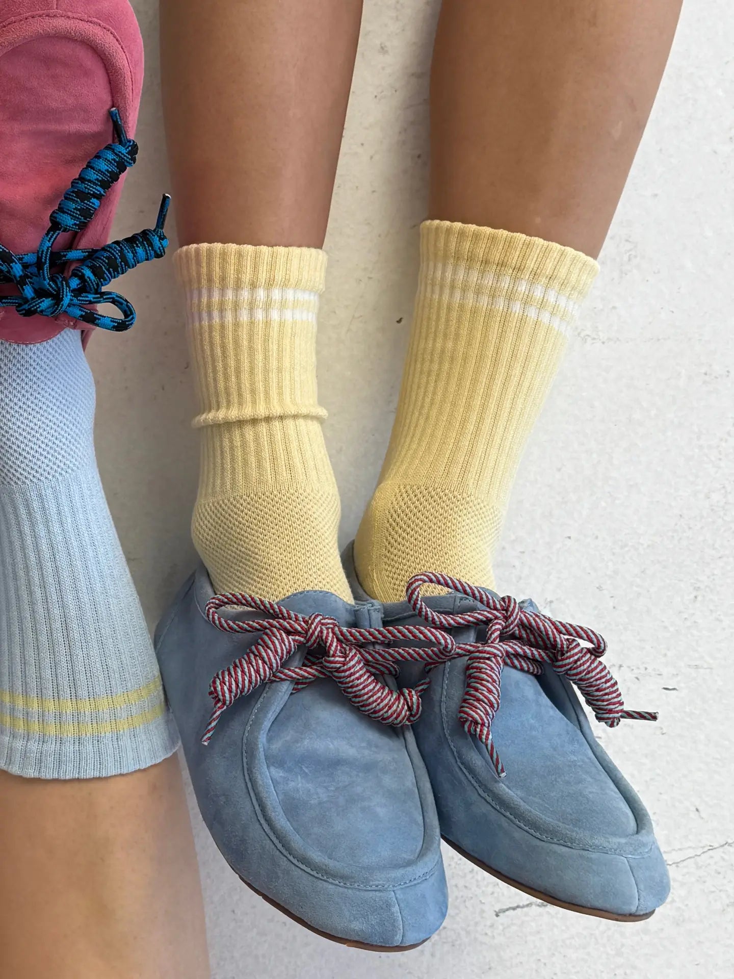 Person wearing yellow socks and blue slippers on a light background