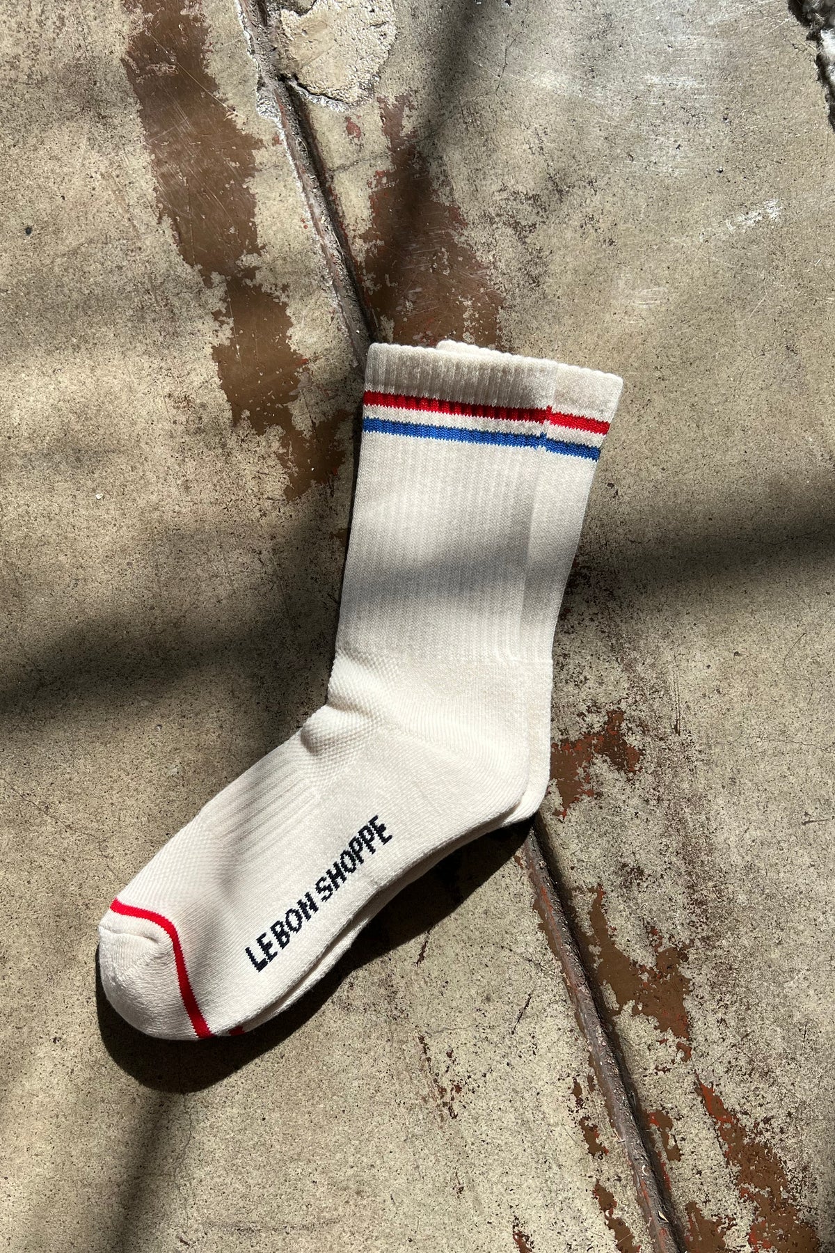 White sock with red and blue stripes on a concrete surface