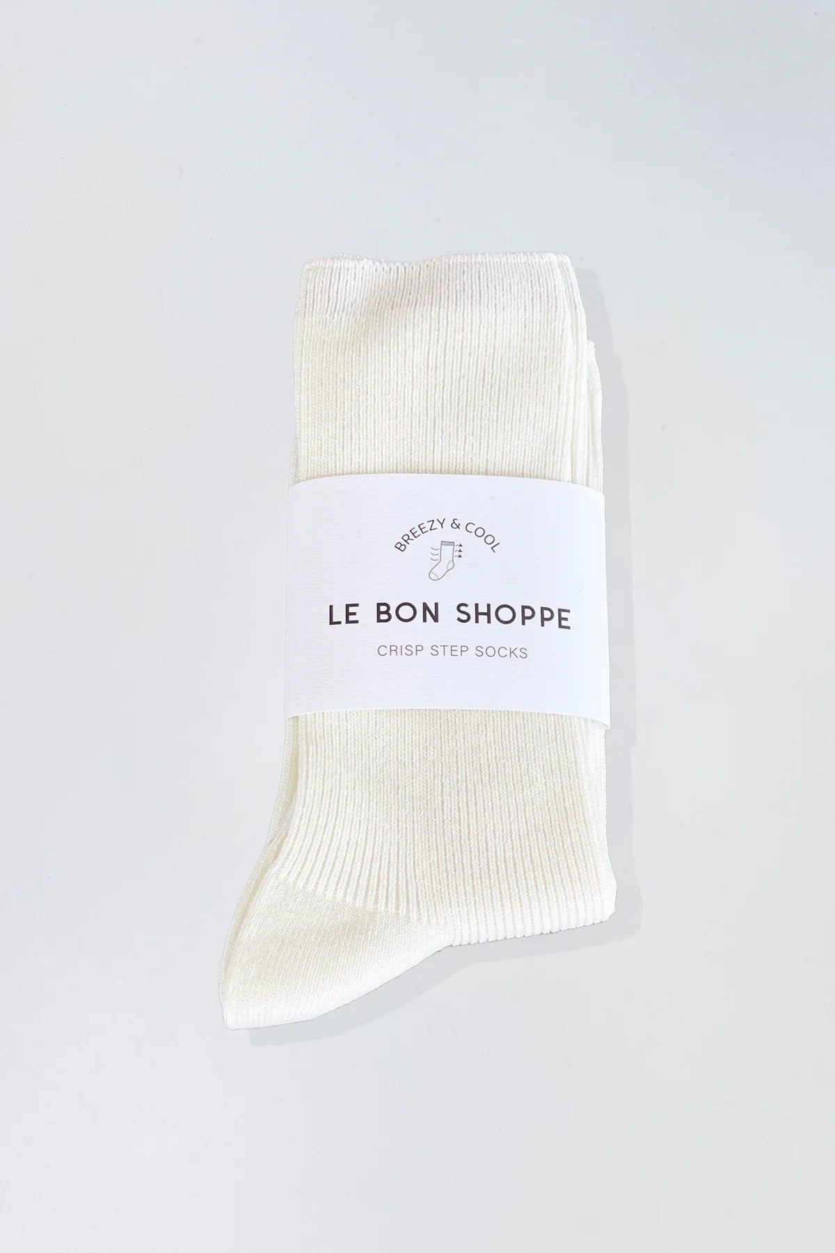 A single off-white ribbed sock with a white paper band label reading 'LE BON SHOPPE' and 'CRISP STEP SOCKS', photographed on a light gray background.