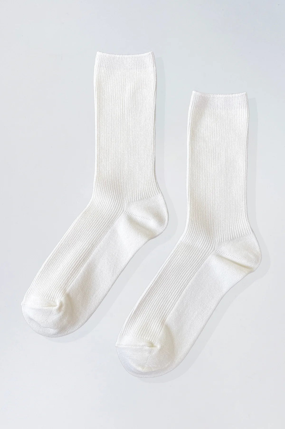 A pair of off-white ribbed crew socks laid flat on a light gray background.