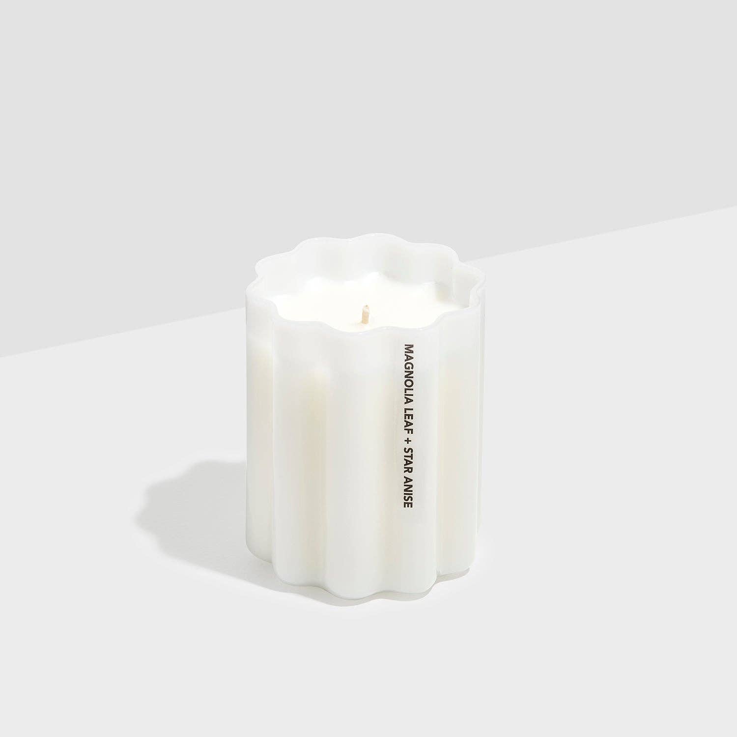 White candle with 'Maison Brulot' branding on a light gray background