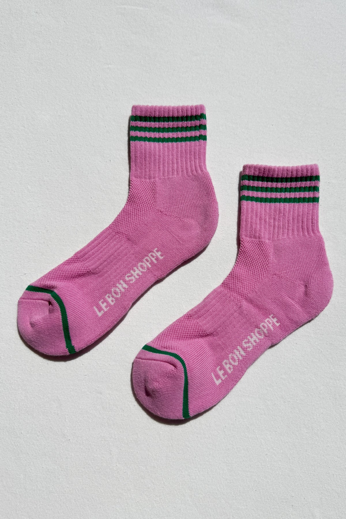 Pink socks with black and green stripes on a light gray background