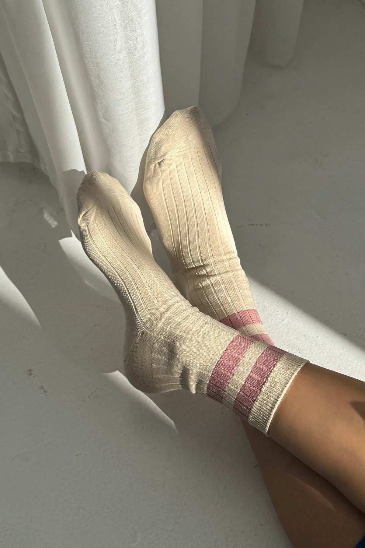 Beige socks with a striped pattern on a white floor.
