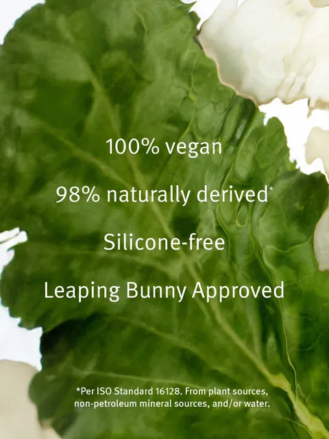 A close-up of a green leaf with white text overlay reading '100% vegan', '98% naturally derived', 'Silicone-free', and 'Leaping Bunny Approved'.
