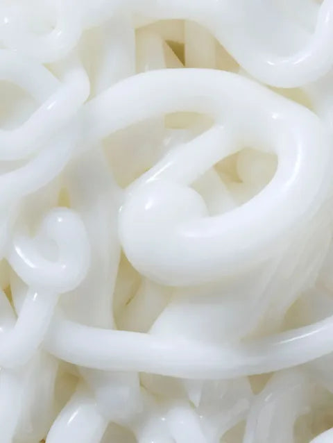 A close-up view of glossy, thick white noodles or rice sticks tangled together.