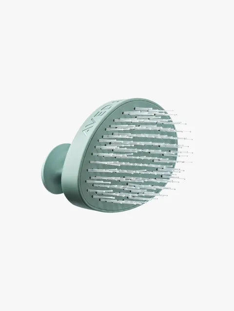 A mint green pet grooming brush with a circular head, featuring white bristles and a visible 'K&H' brand logo on the side, set against a plain light gray background.