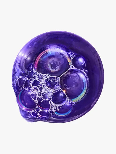 A translucent purple soap bubble with smaller bubbles inside and iridescent rainbow reflections, isolated on a light gray background.