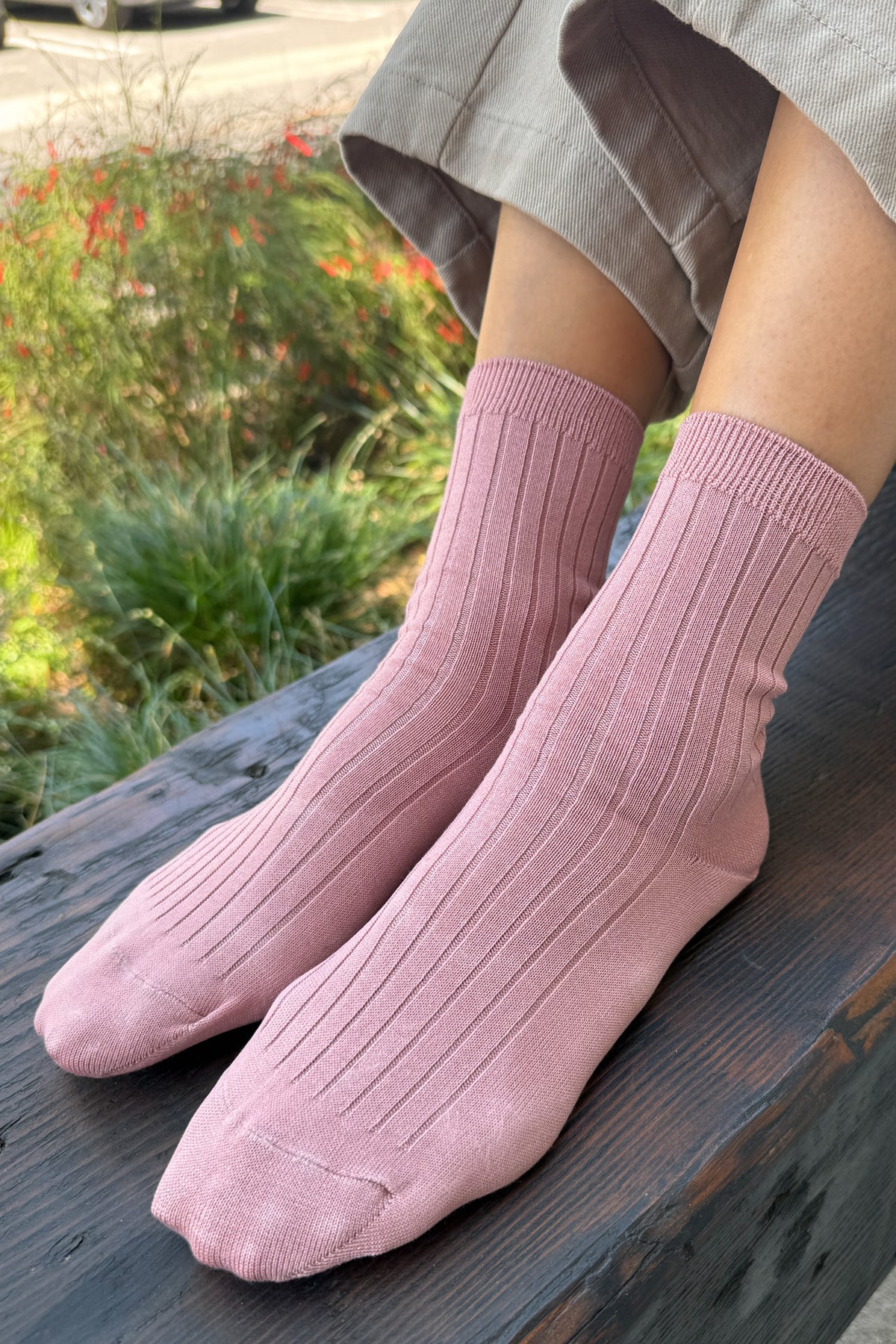 Person wearing pink socks sitting outdoors with a blurred natural background