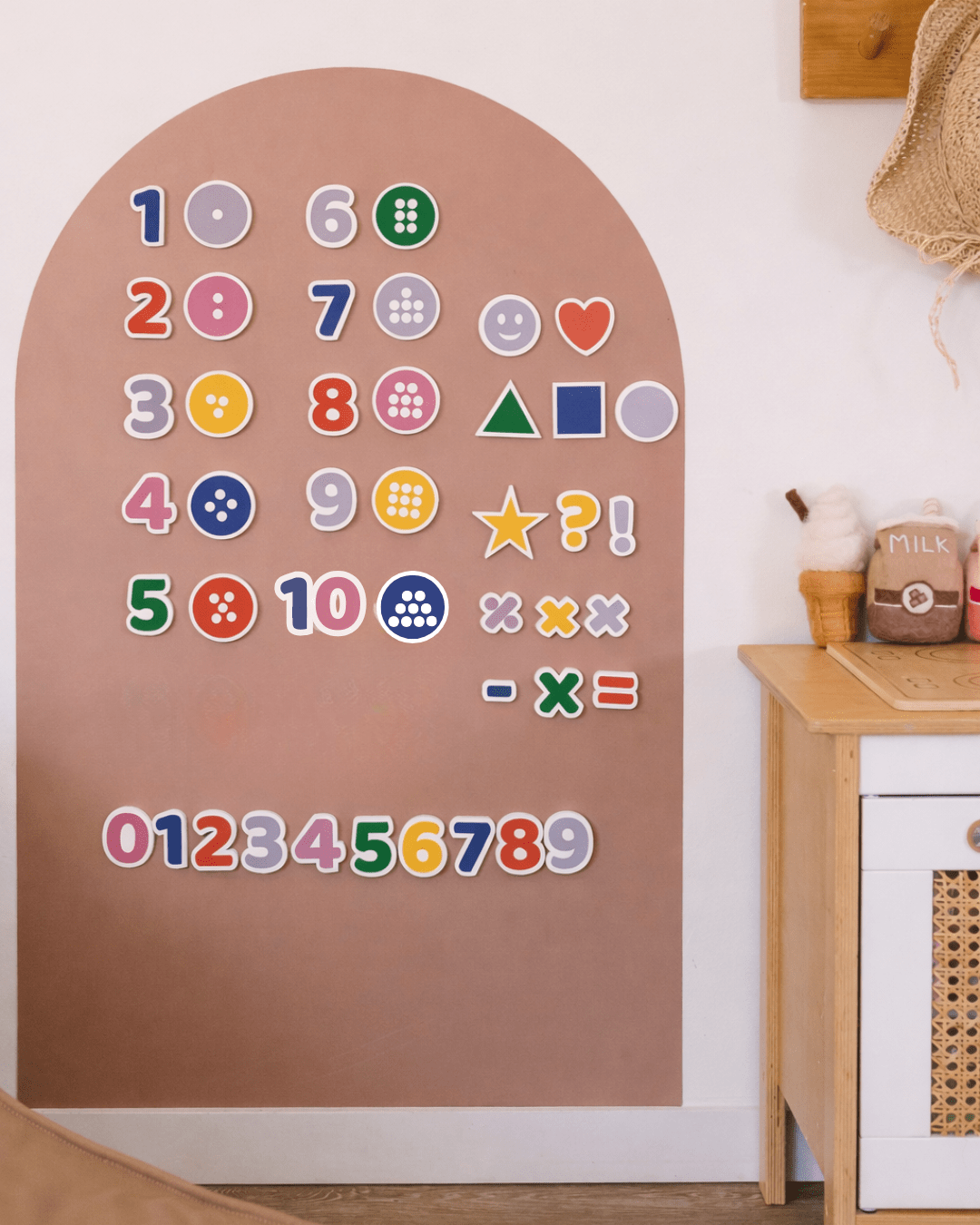 Colorful magnetic letters and numbers on a wooden board against a white wall.