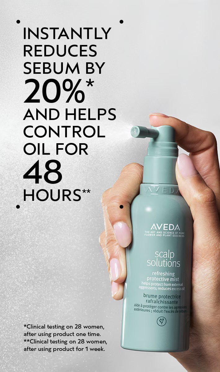Aveda scalp product held by a hand with promotional text on a gray background