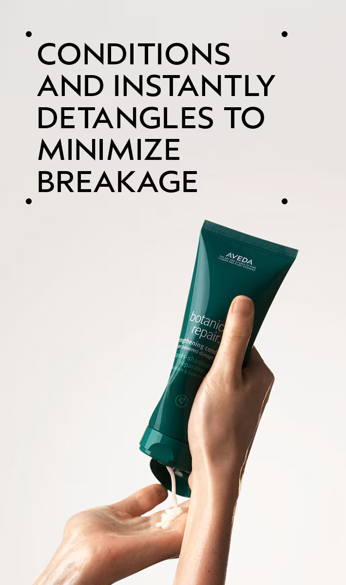 Hand holding a green Aveda product with text about hair care on a light gray background