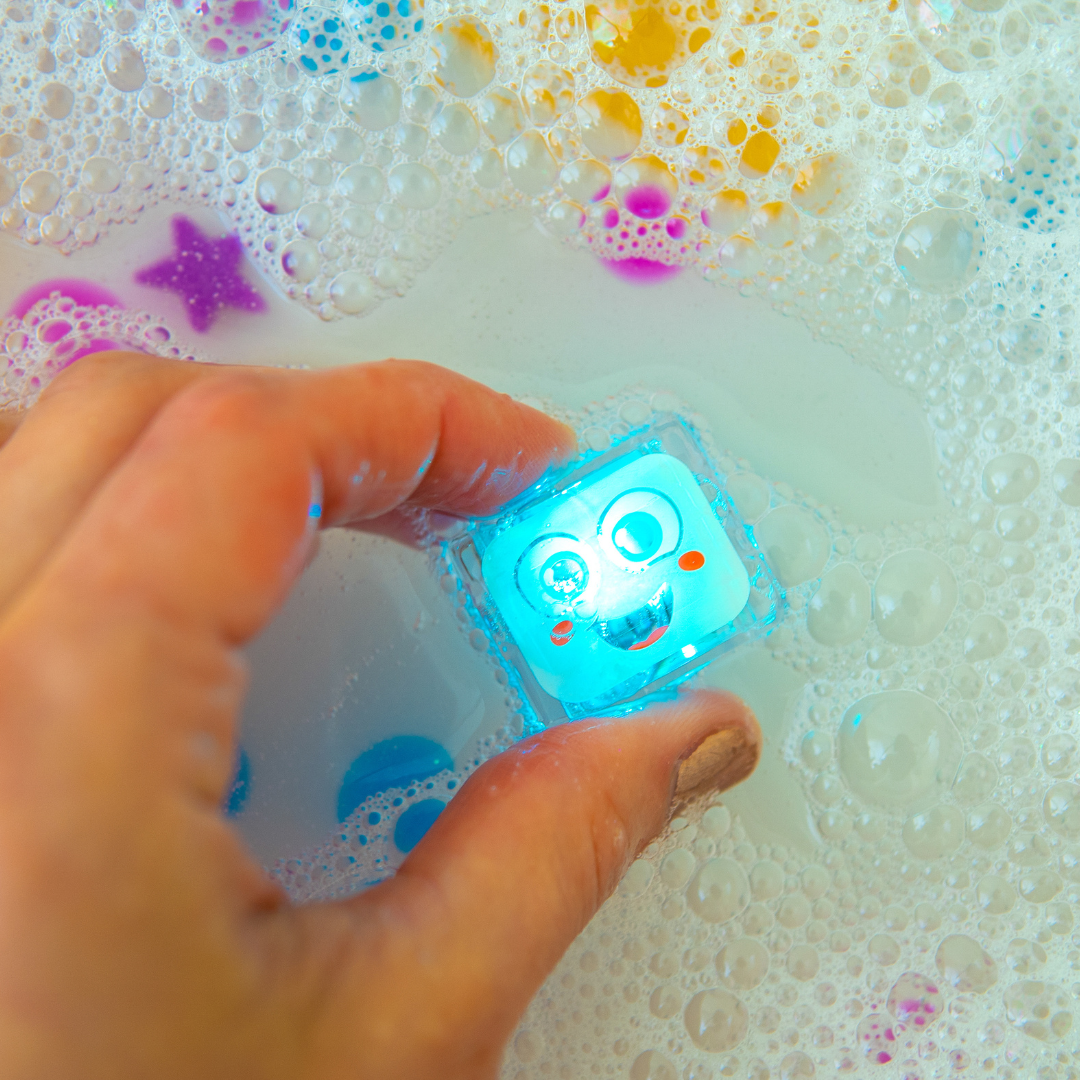 Hand holding a glowing blue cube with a face design over bubbles and water.