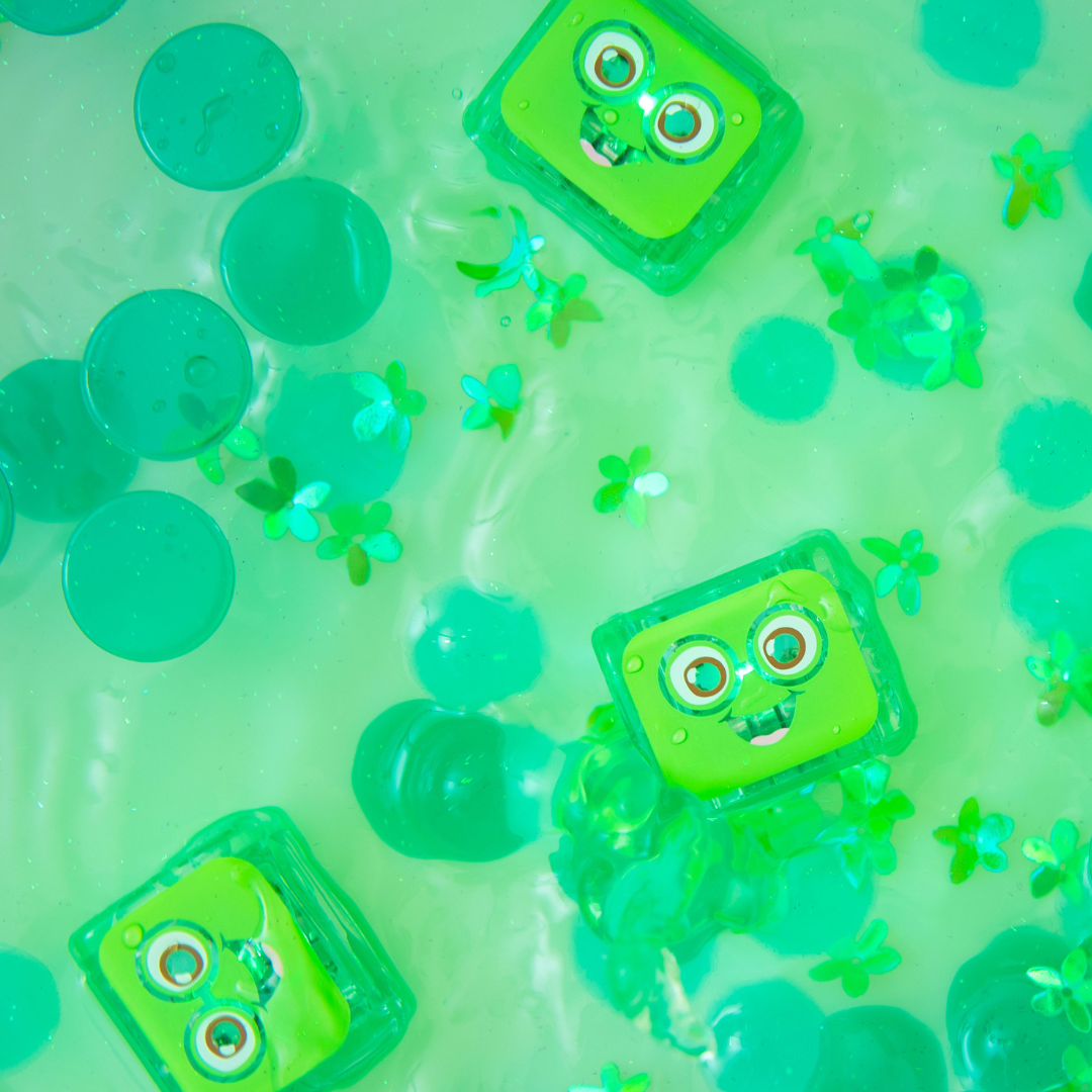 Green toy cassette tapes with googly eyes on a green background