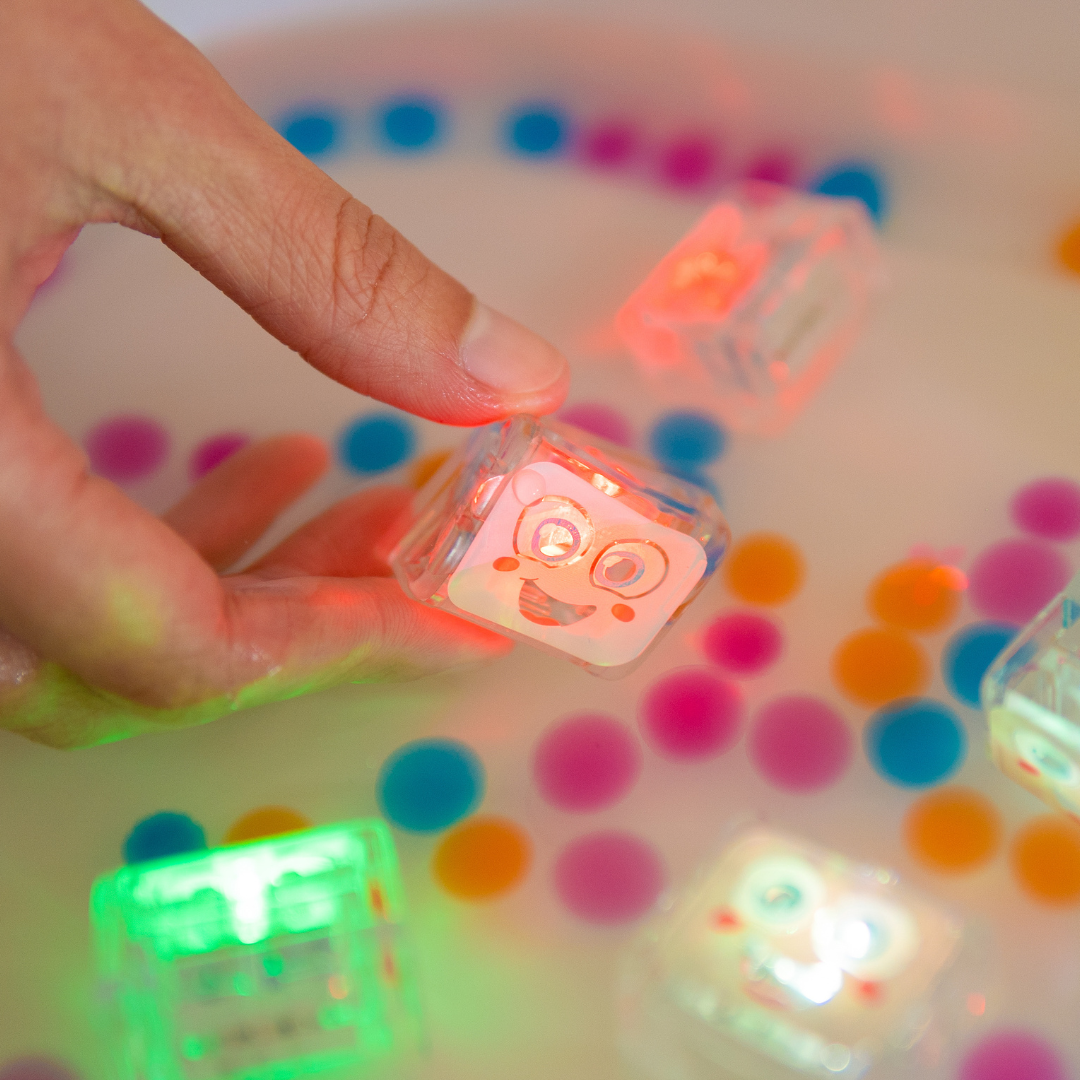 Hand interacting with colorful light-up cubes on a polka dot surface
