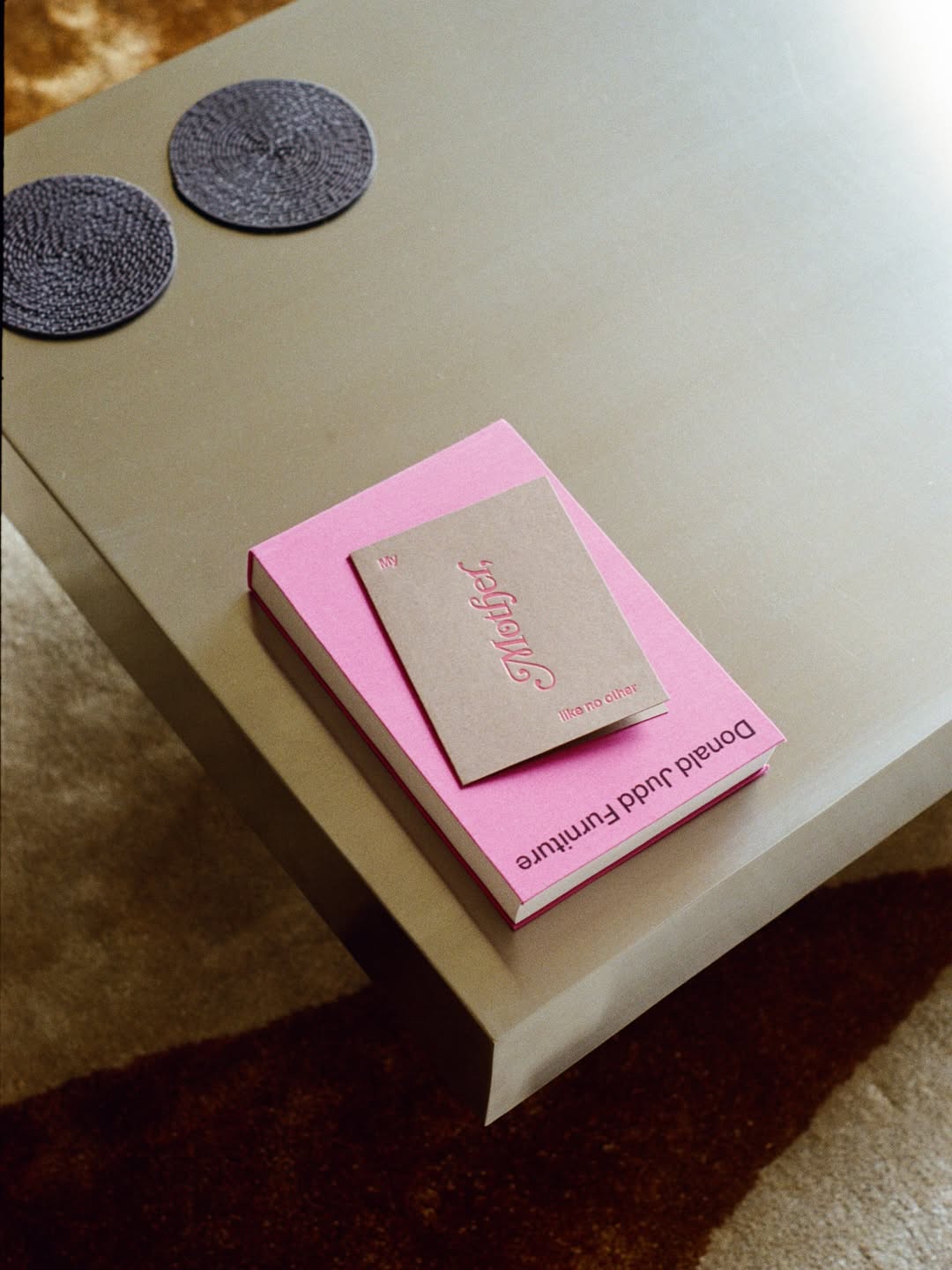 Pink book with a card on top of it on a beige surface