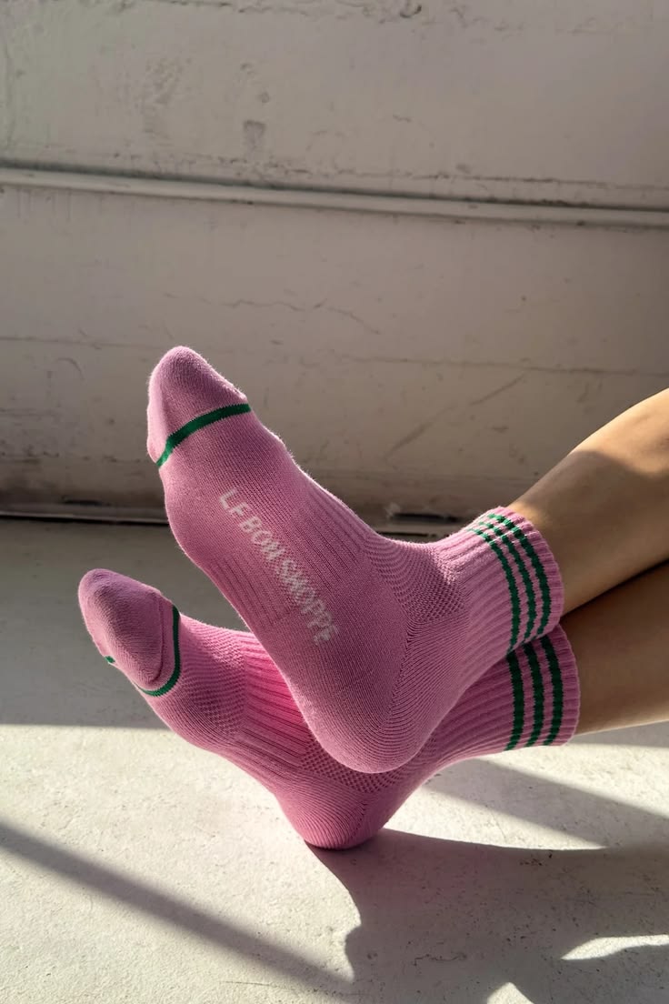 Pink socks with black and green stripes worn by a person on a light-colored floor.