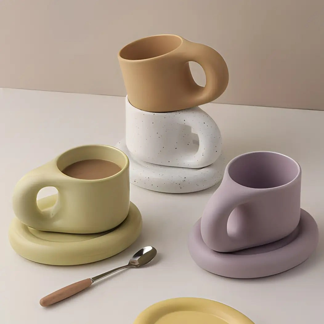 Set of ceramic mugs and coasters with a spoon on a light background
