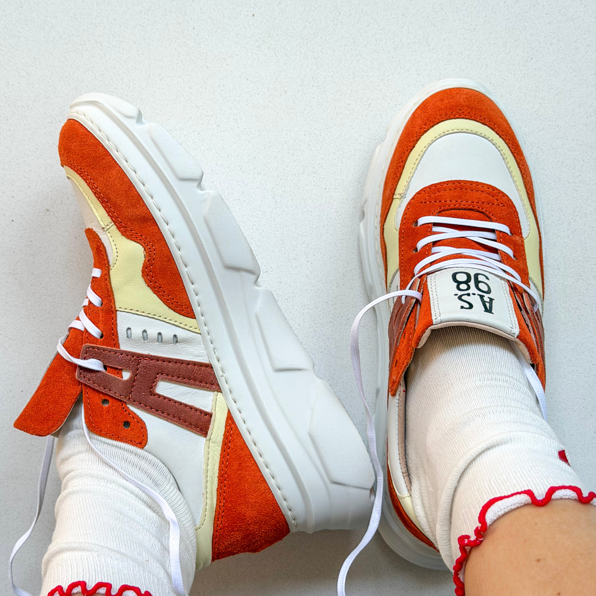 Orange and white sneakers with a brand A.s.98 brand on a light gray background
