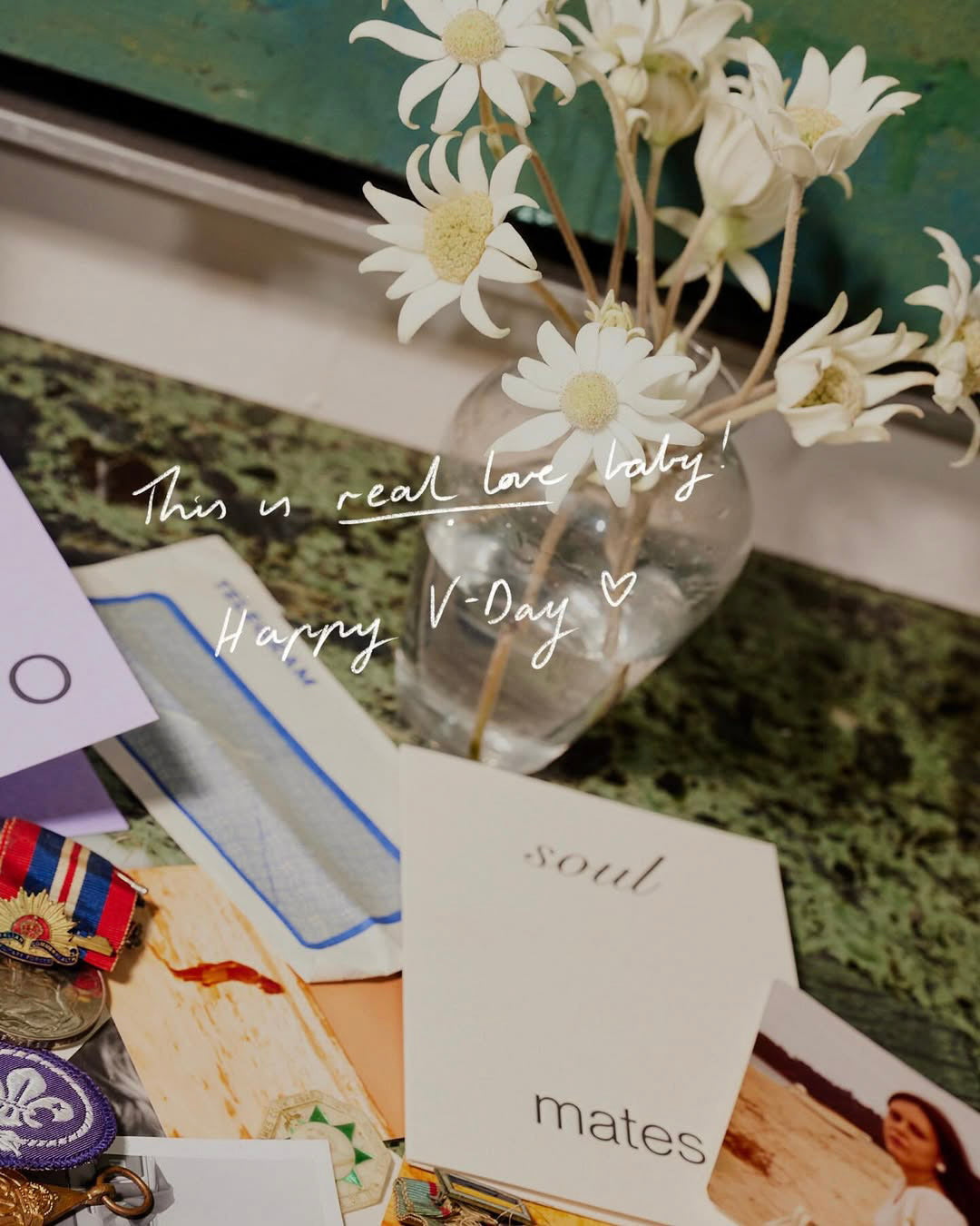 Vase with white flowers on a surface with cards and decorative items.