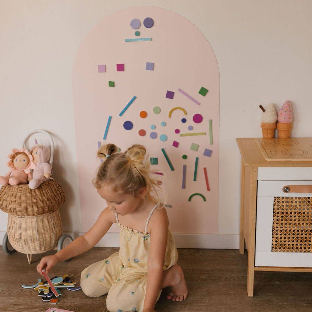 Child playing on the floor with toys in a room with a colorful wall decoration.