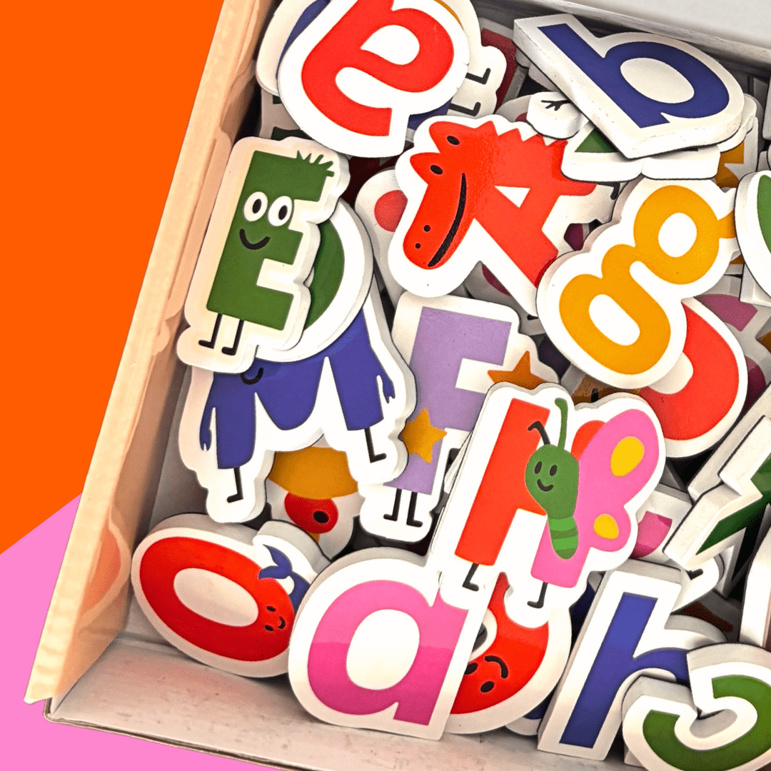 Colorful alphabet letters in a wooden box on an orange and pink background