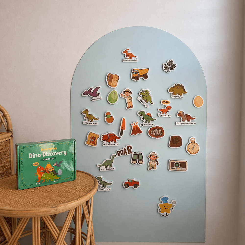 Set of dinosaur-themed magnets on a magnetic board with a box labeled 'Dino Discovery' on a wooden table.