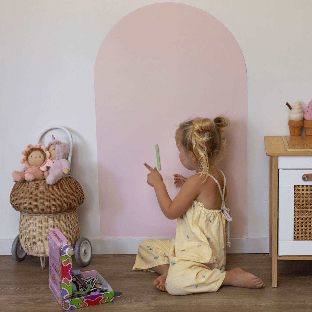 Child playing with toys in a room with a pink archway and wooden furniture.