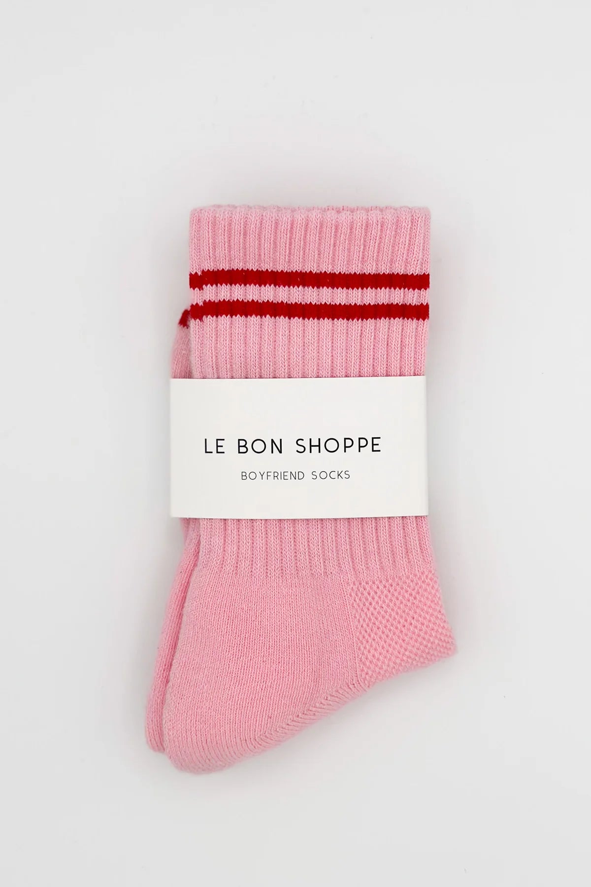 Pair of pink socks with red stripes and 'Le Bon Shoppe' label on a white background