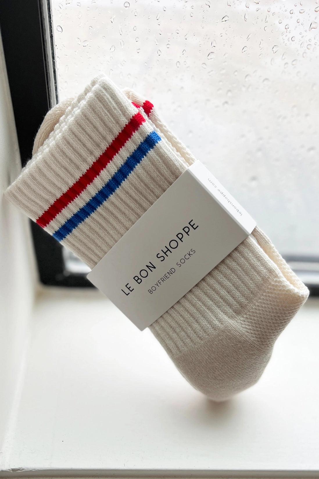 Pair of socks with red, white, and blue stripes on a white surface.