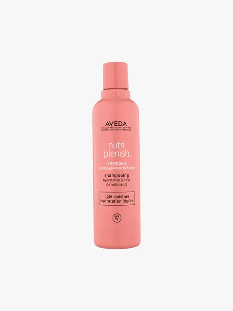 A bottle of Aveda Nutri Plenish Shampoo in a soft coral pink color, centered on a light gray background.