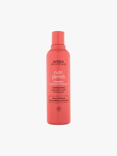 A bottle of Aveda Nutri Plenish Shampoo in a vibrant coral pink color, shown against a plain light gray background.