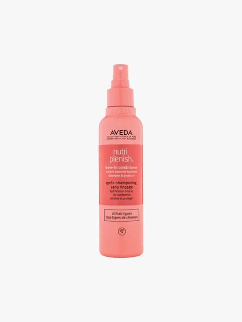 A bottle of Aveda Nutri Plenish Shine-in Conditioner in a coral pink color, shown against a plain light gray background.