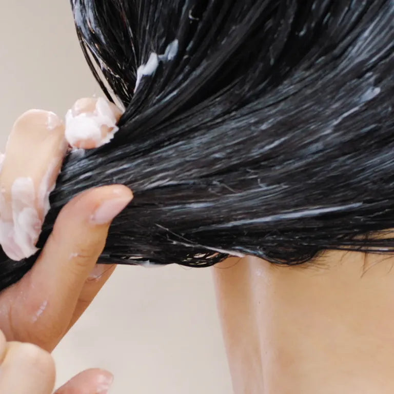 Person applying hair dye to their hair with a brush