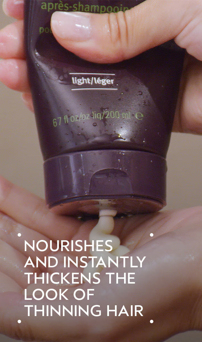 Hand holding a tube of hair product with text about hair thickening.