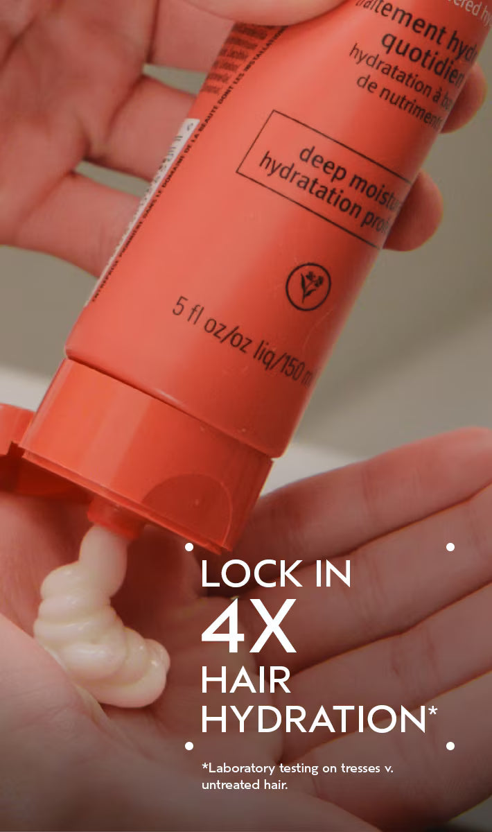 A close-up of hands holding an orange tube of hair hydration product, with a dollop of white cream being squeezed out. White text overlay reads 'LOCK IN 4X HAIR HYDRATION'.