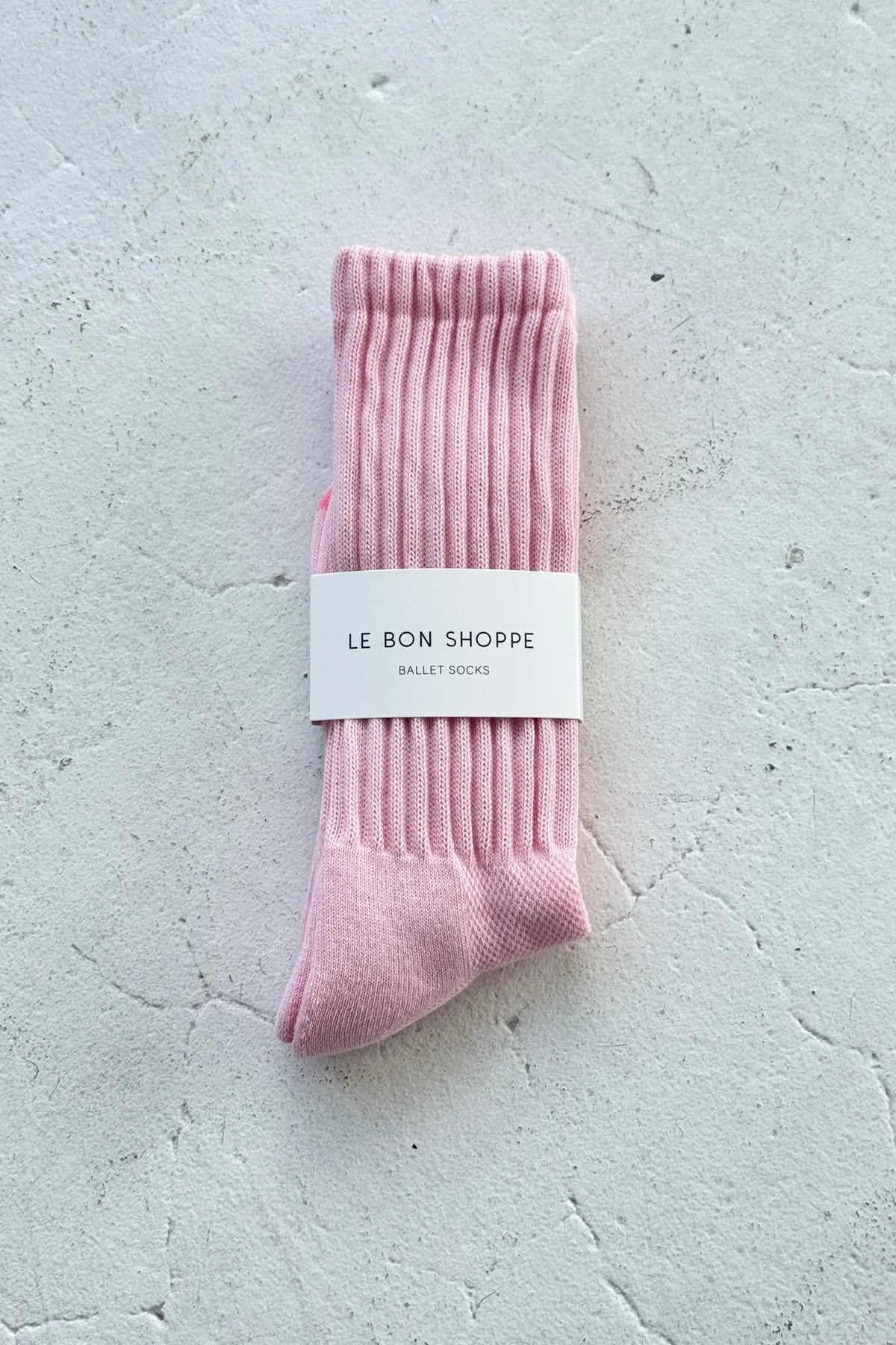 Pink socks with a white label on a light gray surface