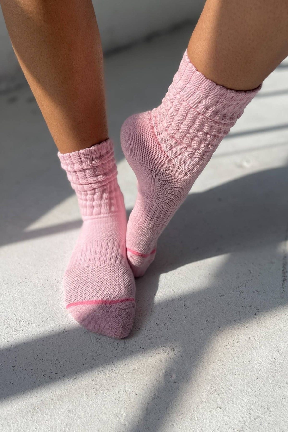 Pink socks worn on a light gray pavement surface