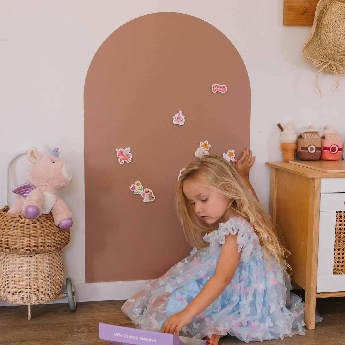 Young girl playing with a toy in a room with a brown arch and wooden furniture.