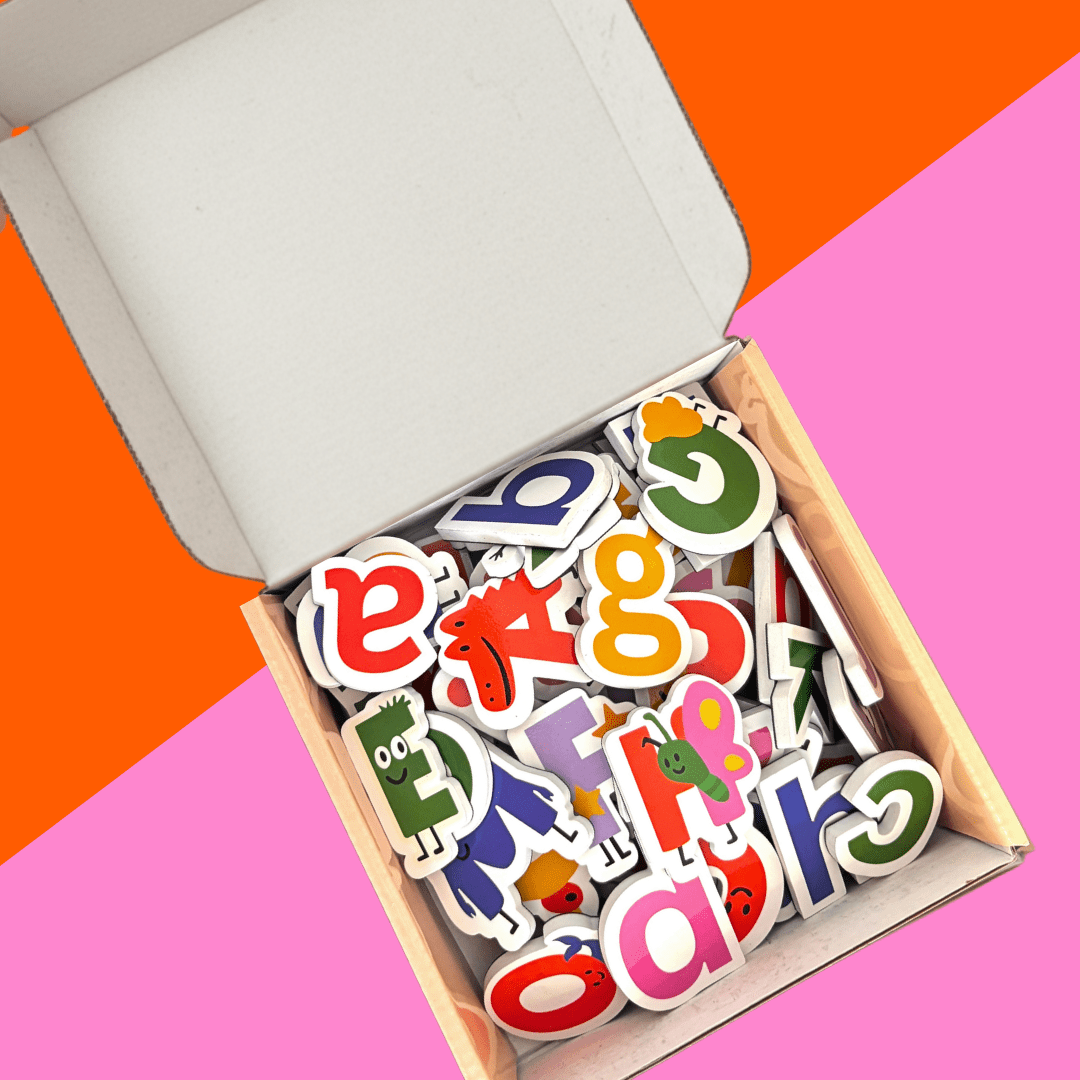 Colorful alphabet letter magnets in a box on a pink and orange geometric background