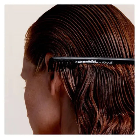 Person combing their hair with a black comb on a plain background