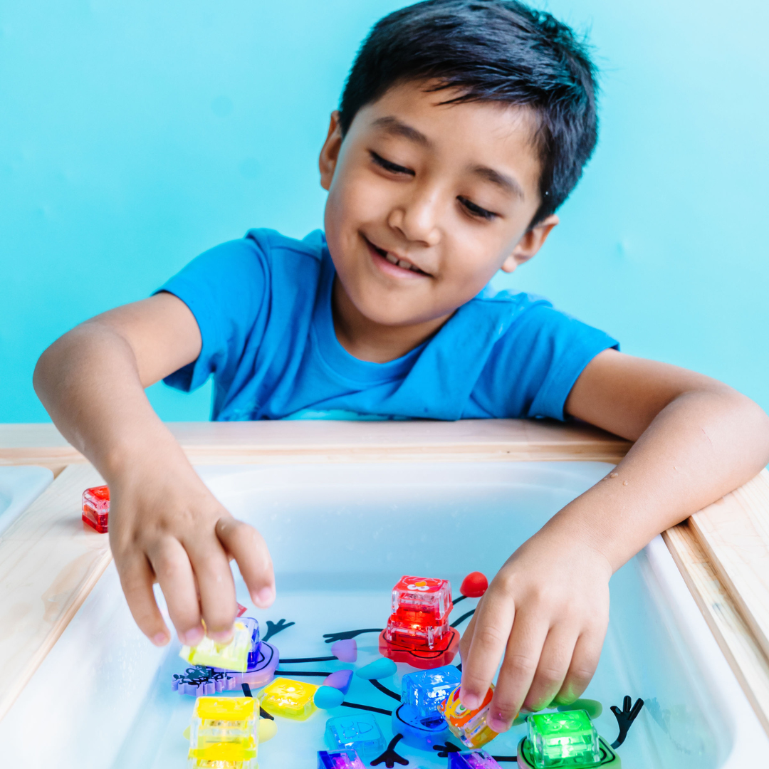Child playing with colorful toys in a water table against a blue background