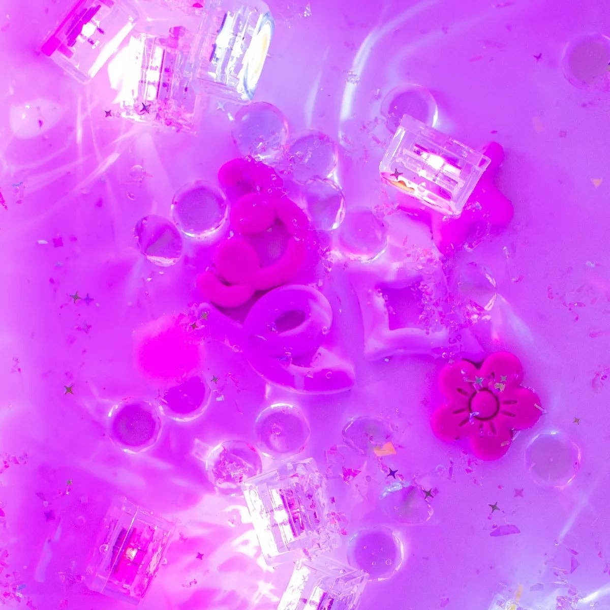 Pink and purple slime with plastic toys and glitter on a pink background