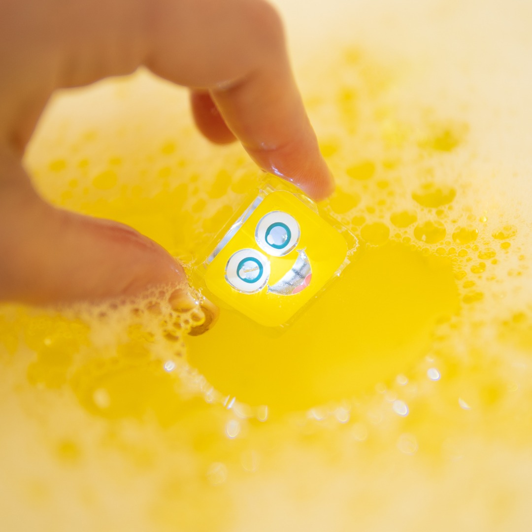 Yellow toy with a face in soapy water