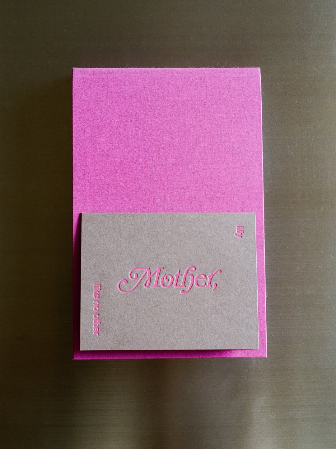 Pink and gray card with 'Mother' text on a dark surface
