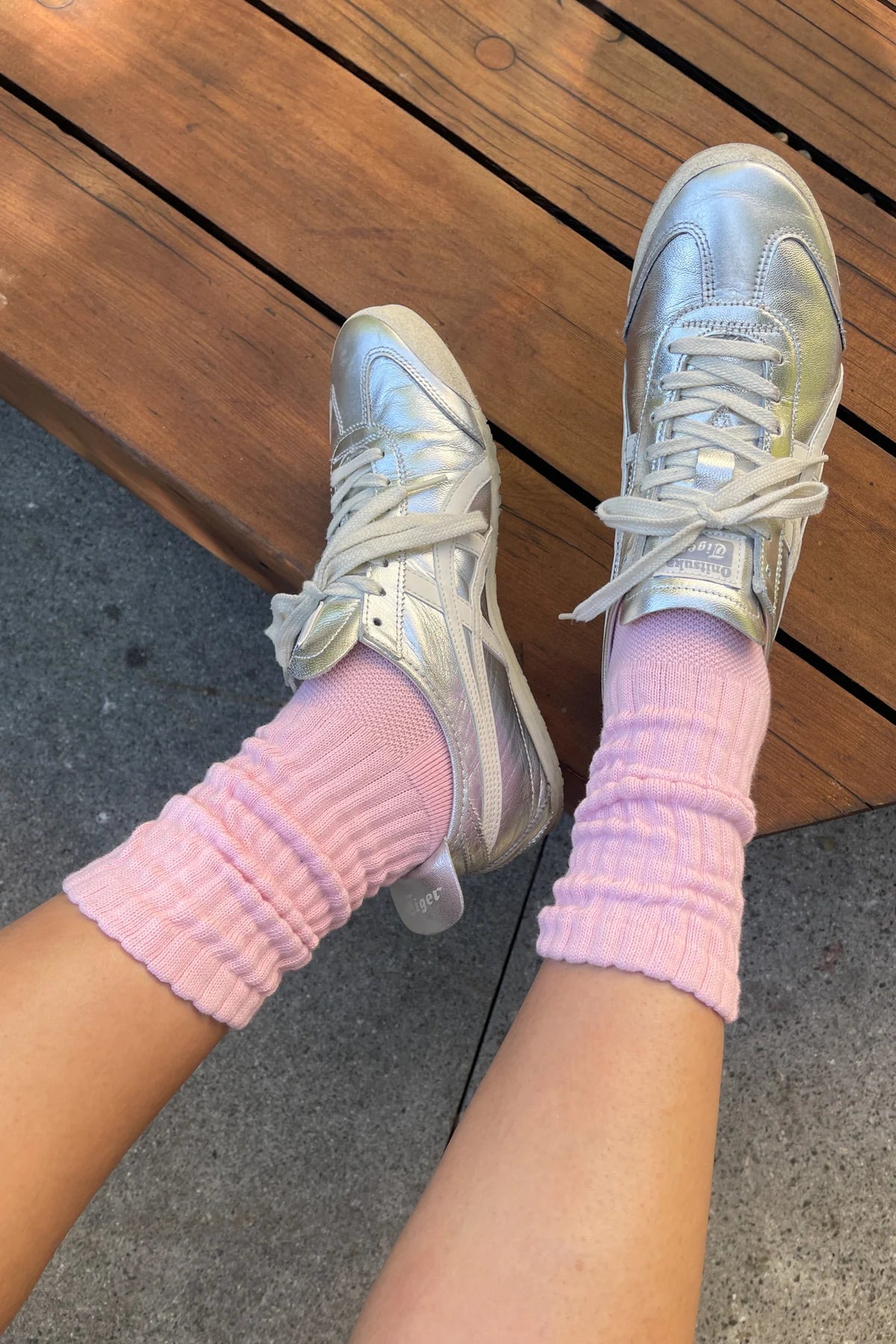 Silver sneakers with pink socks on a wooden floor