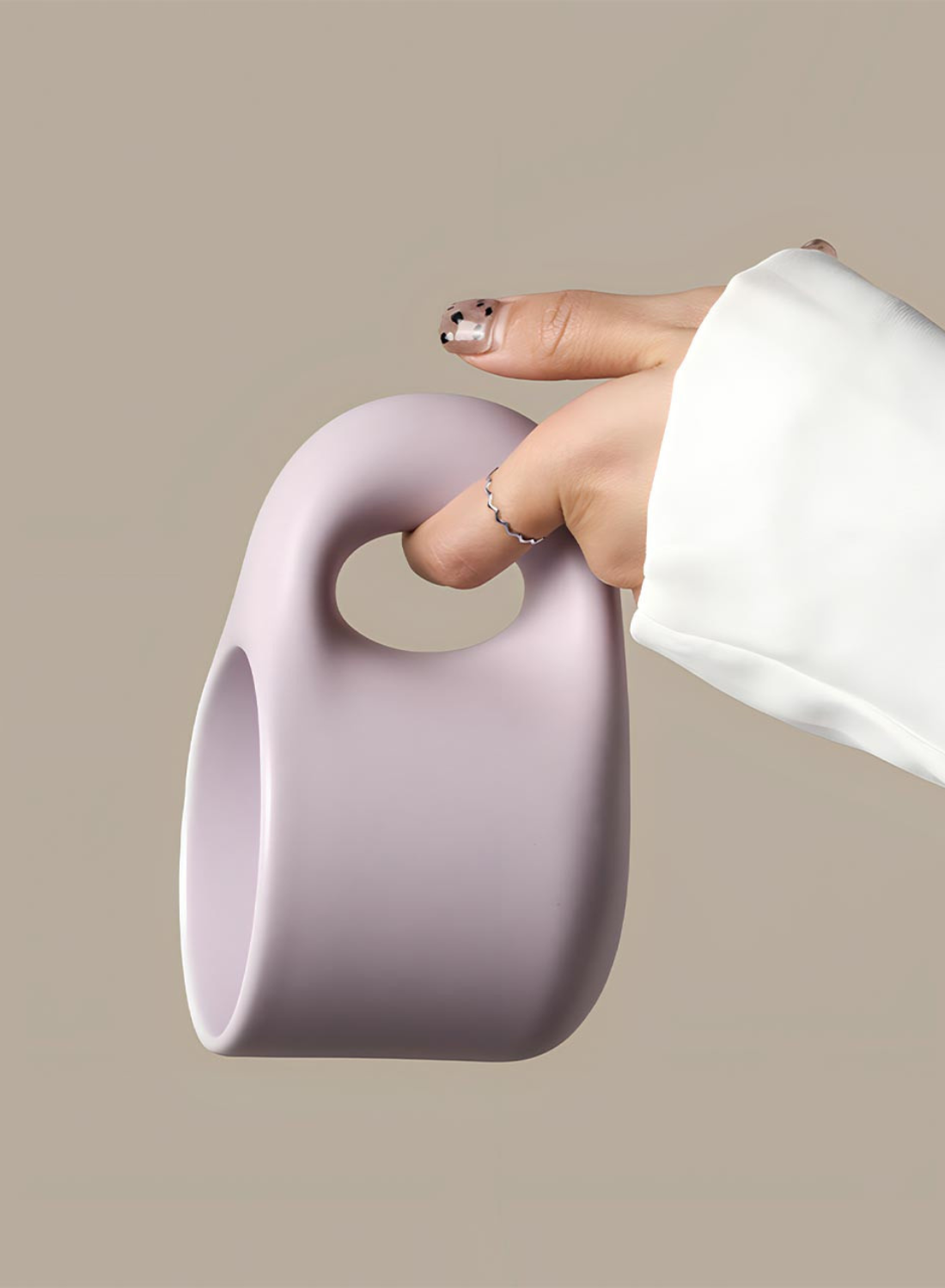 Person holding a light purple ceramic cup against a beige background